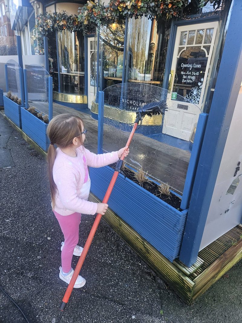 Jay's daughter cleaning the glass screens outside a Poole cafe-bar.