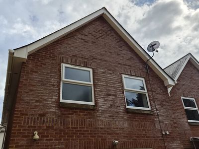 A gable end with clean upstairs windows against a cloudy sky.