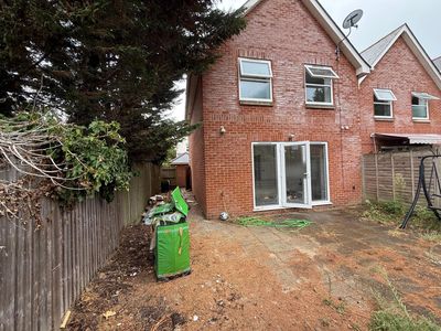 The same patio from the other side, weeds through the slabs.