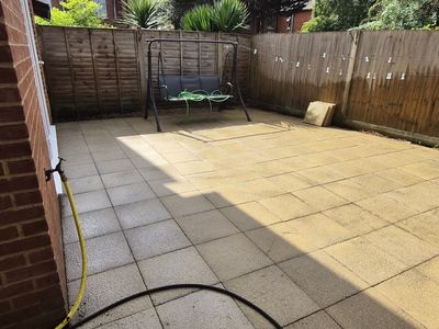 A patio partway through cleaning, clean and dirty slabs side by side.