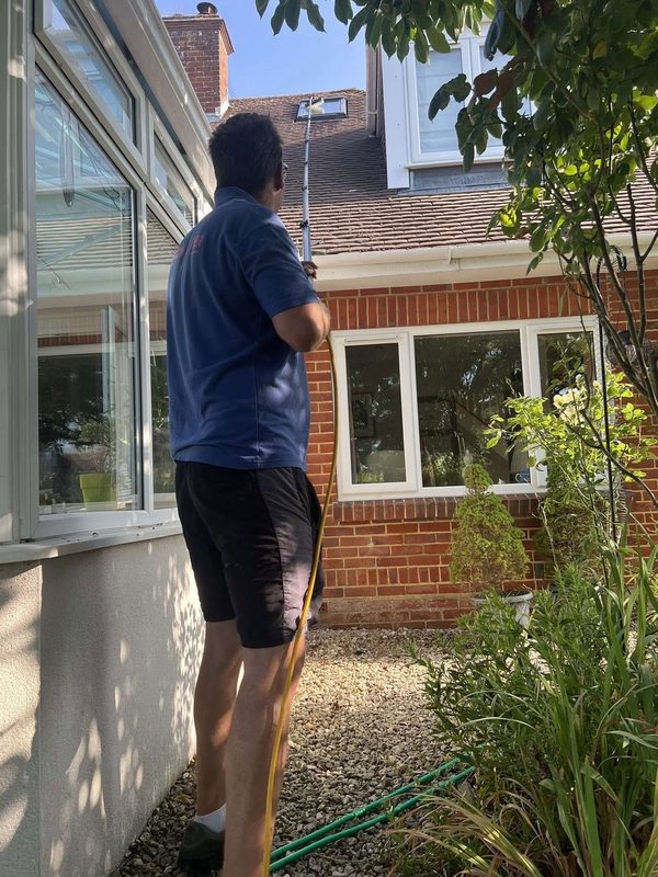 Jay cleaning upstairs windows with a water-fed pole.