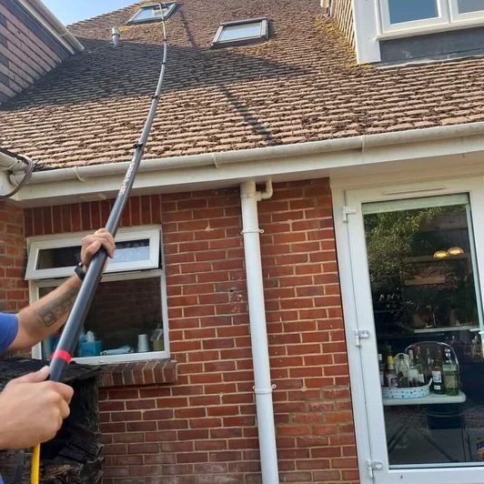 Cleaning upper-floor windows with a water-fed pole.